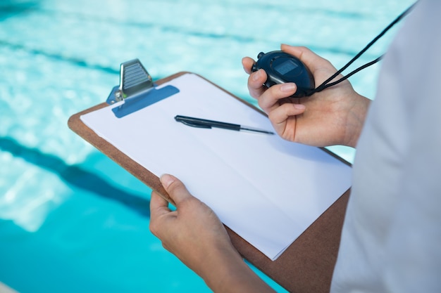 Allenatore di nuoto guardando il cronometro a bordo piscina