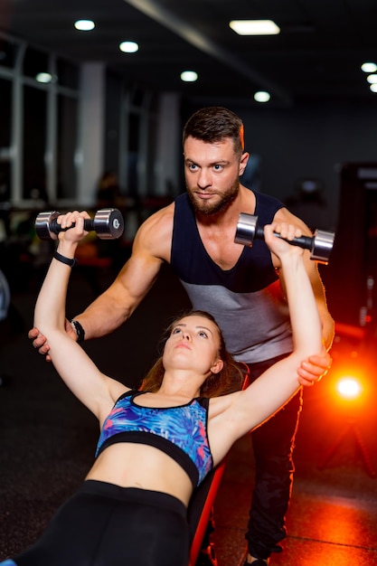 Allenatore uomo e cliente donna in palestra con attrezzature sportive Giovane e in forma Bel corpo forma atletica Sano concetto di vita fitness