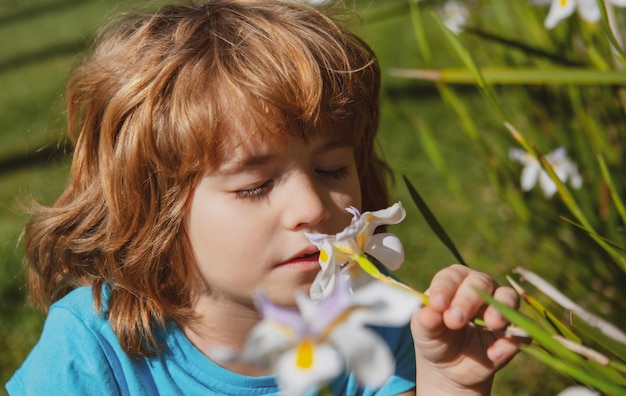 Allergia ai fiori nei bambini Parco primaverile con fiori Ragazzino che annusa il narciso all'aperto