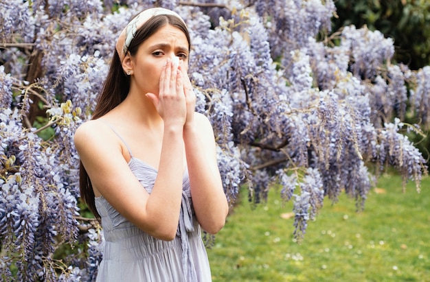 Allergia primaverile ragazza con naso che starnutisce il concetto di sintomo allergico donna allergica ai fiori