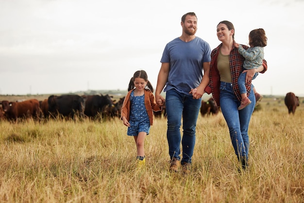 Allevamento di mucche di famiglia di allevatori e legame di madre padre e figli sull'ambiente o sulla sostenibilità della campagna campo agricolo Persone felici e bambini che camminano accanto al bestiame per carne di manzo o industria alimentare