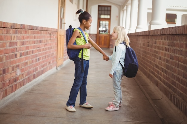 Allievi sorridenti che si tengono per mano al corridoio