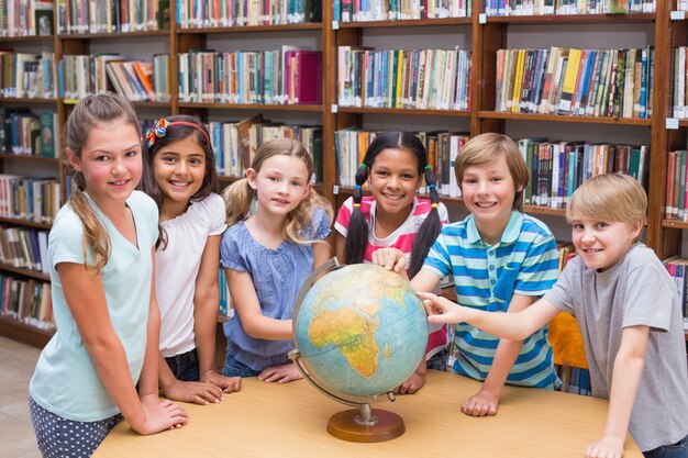 Allievi svegli che esaminano globo in biblioteca