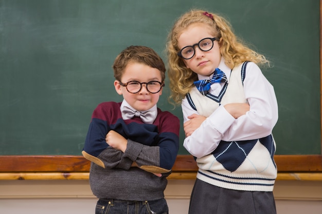 Allievi svegli che esaminano macchina fotografica con le armi attraversate alla scuola elementare