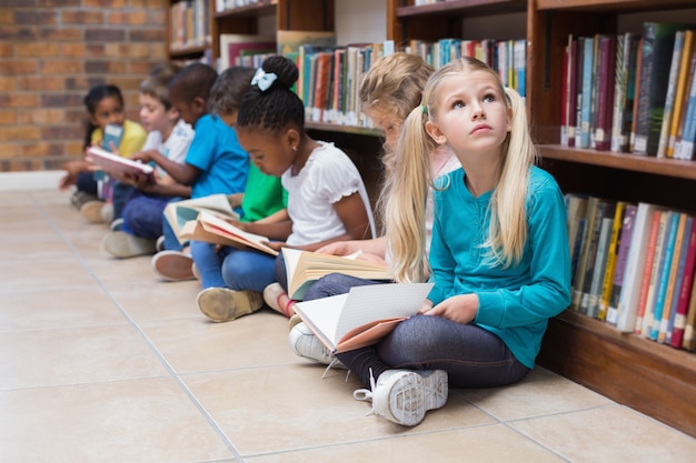 Allievi svegli che si siedono sul pavimento in biblioteca