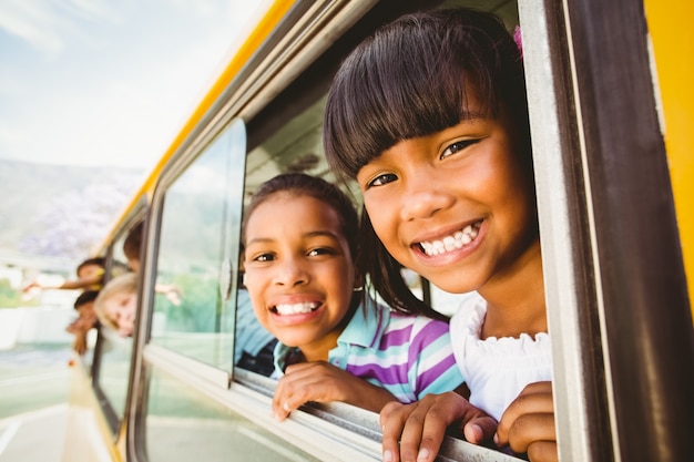 Allievi svegli che sorridono alla macchina fotografica nello scuolabus