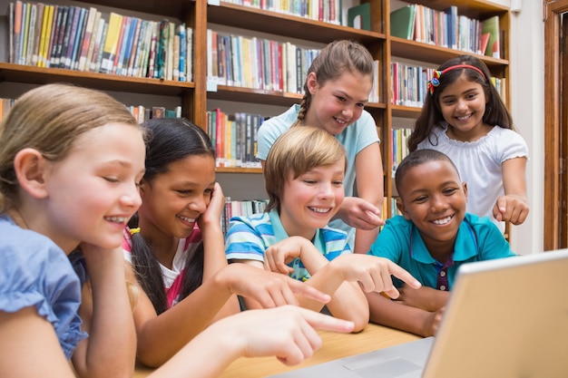 Allievi svegli che utilizzano il computer della compressa nella biblioteca