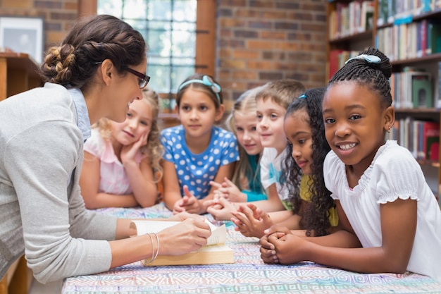 Allievi svegli e insegnante che leggono in biblioteca