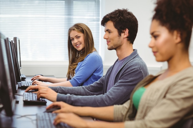 Allievo felice nella classe del computer che sorride alla macchina fotografica