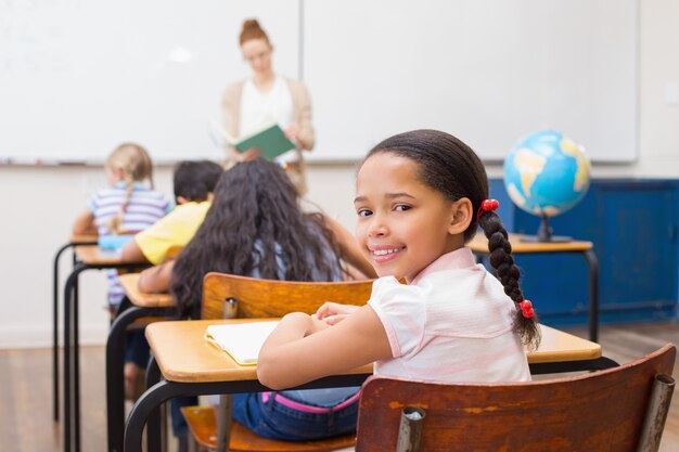 Allievo sveglio che sorride alla macchina fotografica in aula