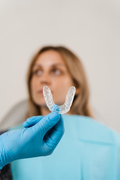 Allineatore trasparente per la correzione del morso e la forma dei denti L'ortodontista mostra un fermo rimovibile trasparente per la donna paziente in odontoiatria