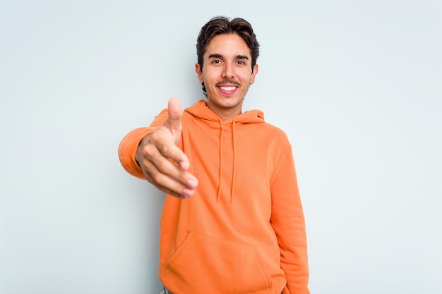 Allungando la mano alla telecamera nel gesto di saluto