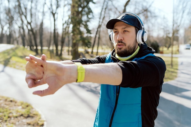 Allungandosi in un parco cittadino preparandosi per un allenamento, lo sportivo che corre allunga le braccia