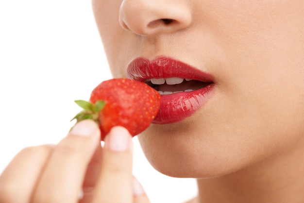 Allure rosso brillante Primo piano ritagliato di una giovane donna con labbra rosse che mangia una fragola