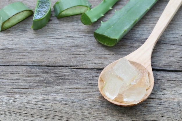 Aloe Vera fresca affettata in cucchiaio di legno sul pavimento di legno marrone.