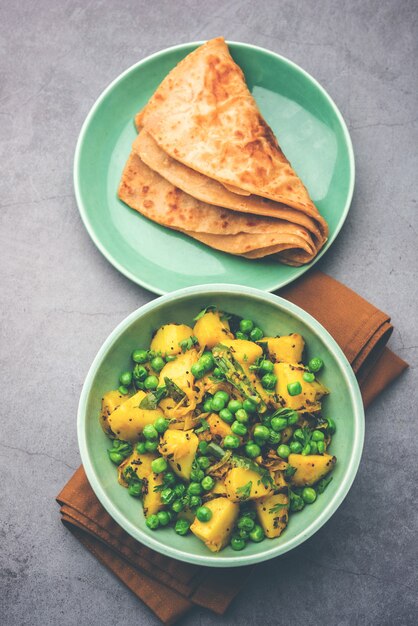 Aloo Mutter o Matar aalu dry sabzi, patate indiane e piselli fritti insieme alle spezie e guarniti con foglie di coriandolo. servito con roti o chapati