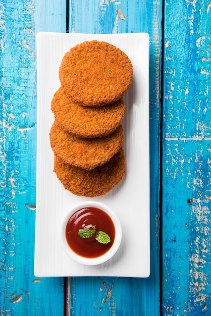 Aloo Tikki o Patties o Cutlet è uno spuntino o uno spuntino popolare dall'India, servito con ketchup di pomodoro o chutney di Imli su uno sfondo lunatico. Messa a fuoco selettiva