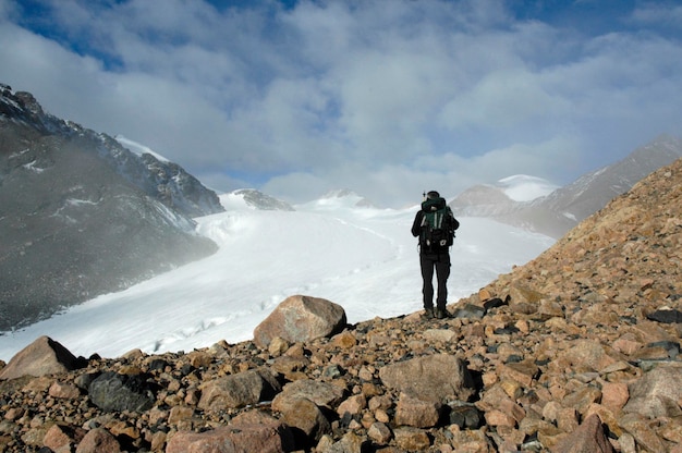Alpinista in piedi su massi di fronte a un ghiacciaio Kharkhiraa Altai mongolo vicino a Ulaangom