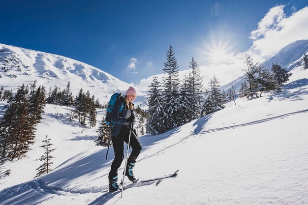 Alpinista sci d'alpinismo a piedi sci alpinista in montagna Sci alpinismo nel paesaggio alpino con alberi innevati Avventura sport invernale