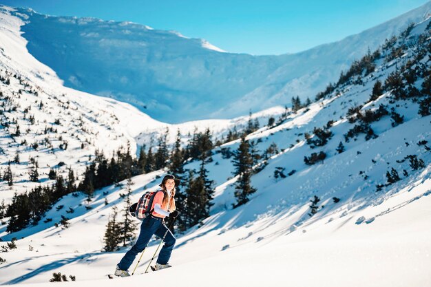 Alpinista sci d'alpinismo a piedi sci alpinista in montagna Sci alpinismo nel paesaggio alpino con alberi innevati Avventura sport invernale