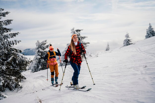 Alpinista sci d'alpinismo a piedi sci donna alpinista in montagna Sci alpinismo nel paesaggio alpino con alberi innevati Avventura sport invernali Sci freeride