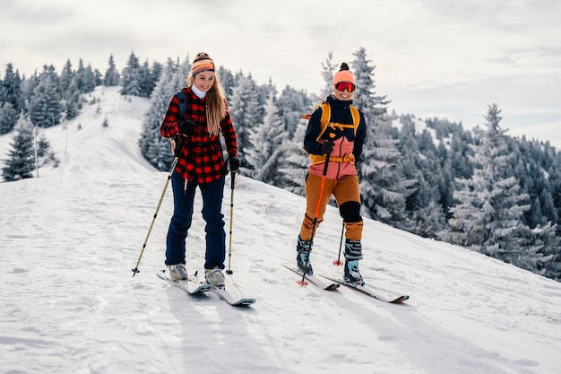 Alpinista sci d'alpinismo a piedi sci donna alpinista in montagna Sci alpinismo nel paesaggio alpino con alberi innevati Avventura sport invernali Sci freeride