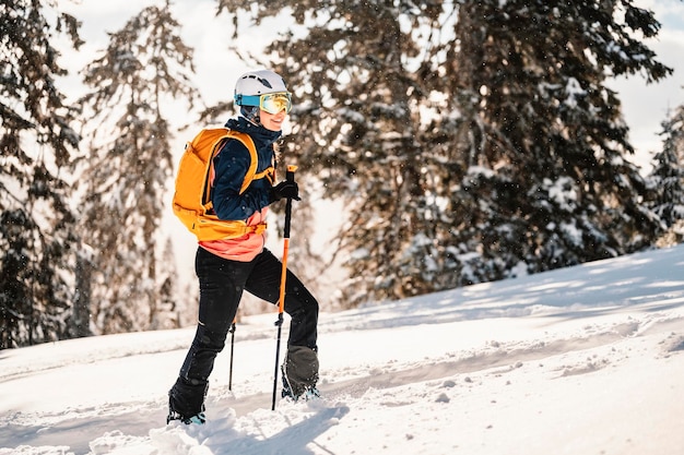 Alpinista sci d'alpinismo a piedi sci donna alpinista in montagna Sci alpinismo nel paesaggio alpino con alberi innevati Avventura sport invernali Sci freeride