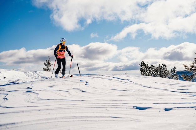 Alpinista sci d'alpinismo a piedi sci donna alpinista in montagna Sci alpinismo nel paesaggio alpino con alberi innevati Avventura sport invernali Sci freeride