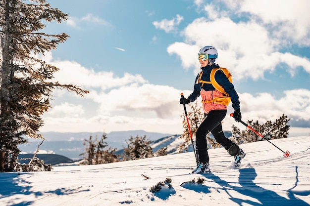 Alpinista sci d'alpinismo a piedi sci donna alpinista in montagna Sci alpinismo nel paesaggio alpino con alberi innevati Avventura sport invernali Sci freeride