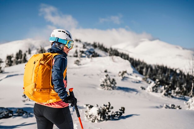 Alpinista sci d'alpinismo a piedi sci donna alpinista in montagna Sci alpinismo nel paesaggio alpino con alberi innevati Avventura sport invernali Sci freeride