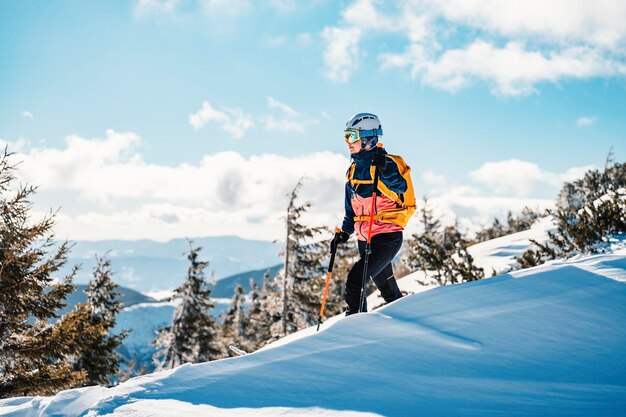 Alpinista sci d'alpinismo a piedi sci donna alpinista in montagna Sci alpinismo nel paesaggio alpino con alberi innevati Avventura sport invernali Sci freeride