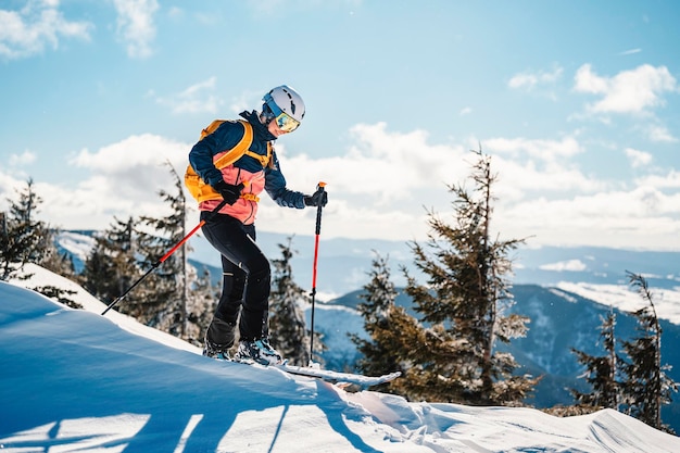 Alpinista sci d'alpinismo a piedi sci donna alpinista in montagna Sci alpinismo nel paesaggio alpino con alberi innevati Avventura sport invernali Sci freeride