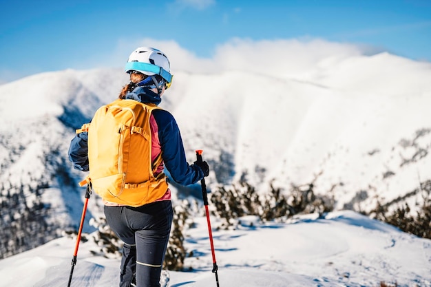 Alpinista sci d'alpinismo a piedi sci donna alpinista in montagna Sci alpinismo nel paesaggio alpino con alberi innevati Avventura sport invernali Sci freeride