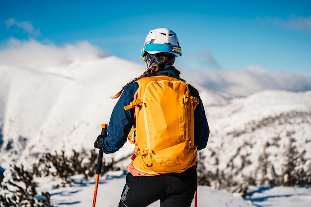 Alpinista sci d'alpinismo a piedi sci donna alpinista in montagna Sci alpinismo nel paesaggio alpino con alberi innevati Avventura sport invernali Sci freeride