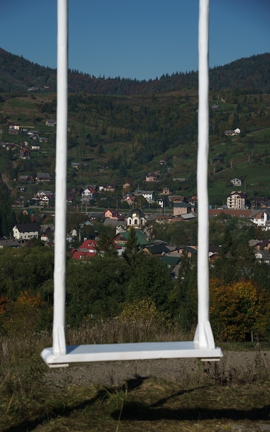 Altalena bianca sulle montagne con vista sul villaggio in Ucraina