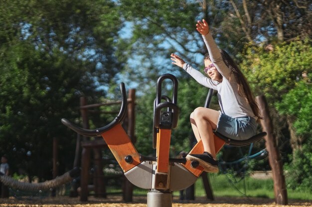 Altalena caucasica di filatura bella ragazza nel parco al parco giochi