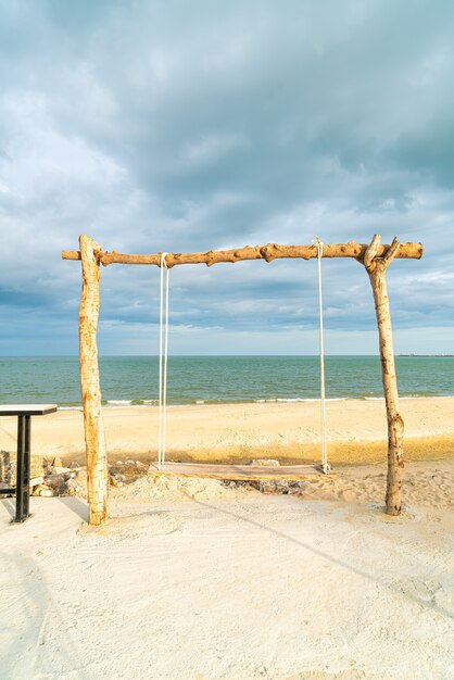 altalena in legno sulla spiaggia con sfondo spiaggia mare