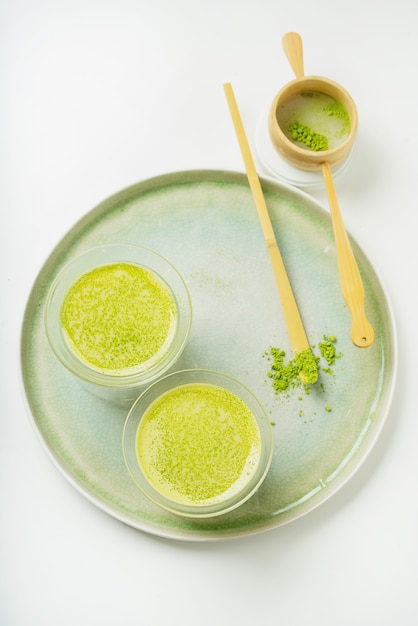 Alternativa salutare al caffè matcha latte su un vassoio in ceramica decorato con polvere di matcha, cucchiaio di bambù chashaku e colino. Lay piatto. Vista dall'alto