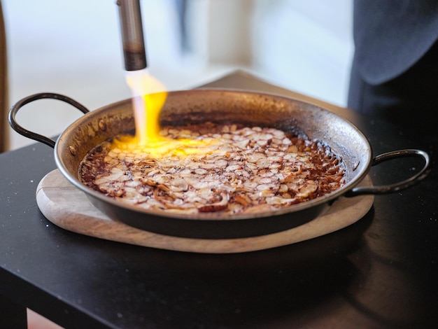 Alto angolo dello chef che utilizza il fornello per cucinare la paella tradizionale su sfondo sfocato