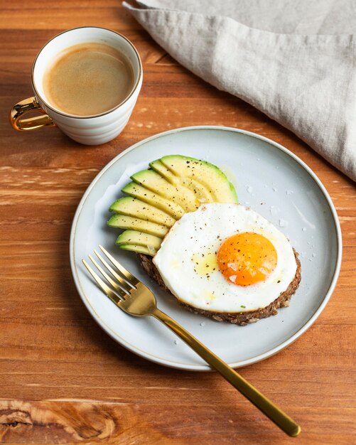 Alto angolo di colazione uovo fritto sulla piastra con avocado e caffè