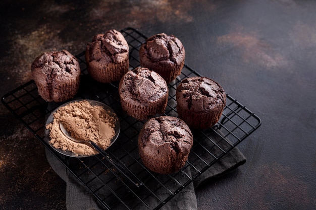 Alto angolo di muffin al cioccolato su griglia di raffreddamento con cacao in polvere