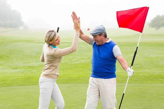 Alto fiving golfing delle coppie sul campo da golf un giorno nebbioso al campo da golf