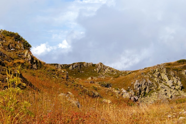 Altopiano roccioso con erba secca e nuvole sullo sfondo