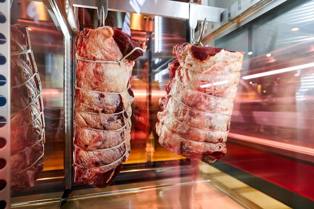 altre due carcasse di carne sospese su ganci appesi nel frigorifero