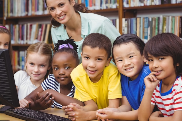 Alunni e insegnante nella biblioteca utilizzando il computer