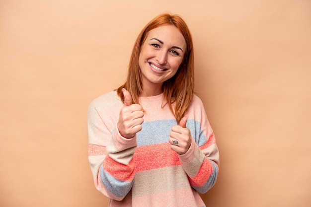 Alzando entrambi i pollici in su sorridente e fiducioso