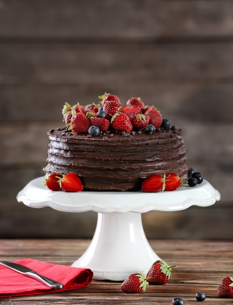 Alzata per dessert con gustosa torta al cioccolato su tavola di legno