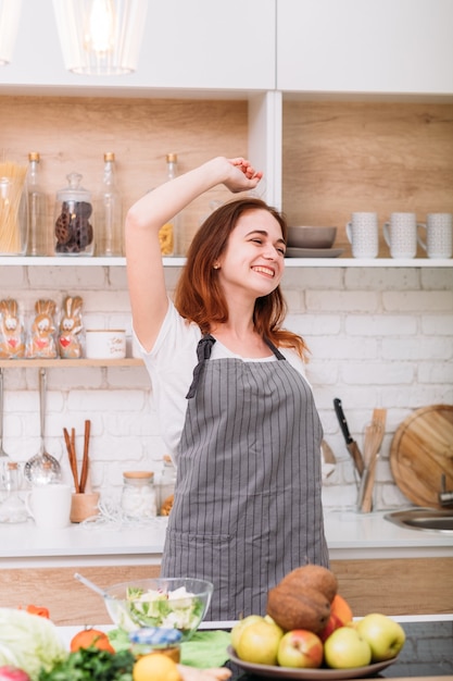 Ama cucinare. Hobby e stile di vita. Carino giovane donna che indossa grembiule ballare in cucina.