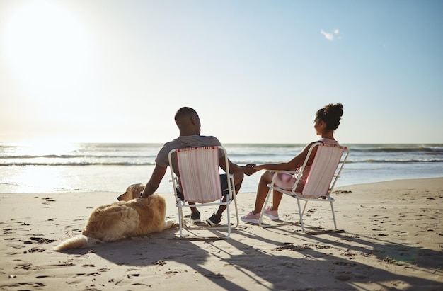 Ama il cane o la famiglia nera che si tiene per mano sulla spiaggia dell'oceano o del mare per il tramonto che parla di legame o si rilassa il giorno d'estate Viaggio in famiglia o donna e uomo di colore per sostegno fiduciario o vacanza al tramonto