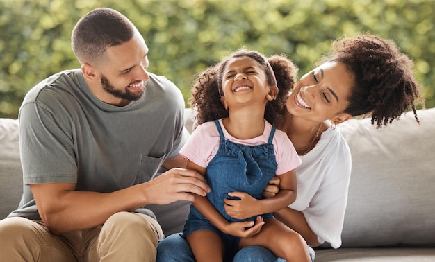 Ama il relax e la famiglia felice ride insieme sul divano per il tempo libero in Messico con genitori premurosi Madre e padre messicani si divertono a fare il solletico sul divano con la figlia piccola per divertirsi insieme